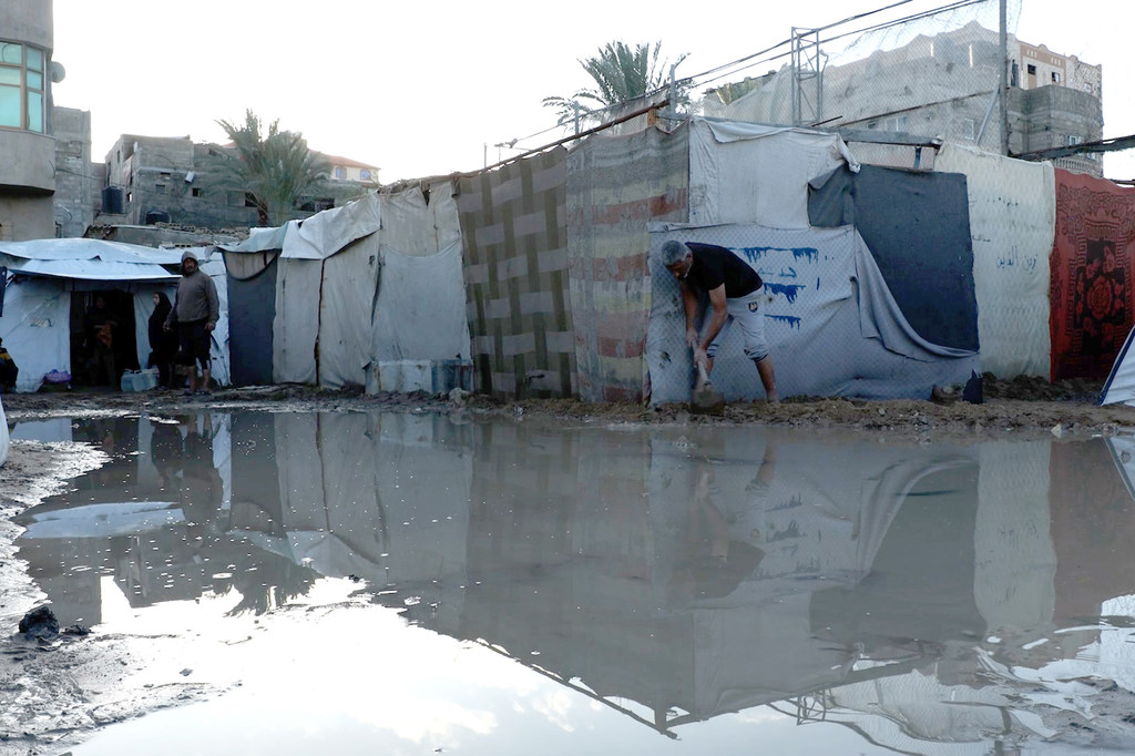 يقوم الأهالي ببناء حواجز رملية حول خيامهم بعد أن غمرتها الأمطار الغزيرة لمنع دخول المياه إليها مرة أخرى.